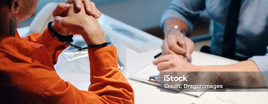 Criminal in Handcuffs Talking to Detective filling witness statement forms